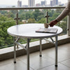 Foldable Stainless Steel Table with a cup and newspaper, perfect for outdoor or indoor use.
