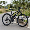 Enduro Mountain Bike with Aluminum Frame and Disc Brakes on a pathway surrounded by greenery.