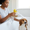 Person using the ABS Pet Bubble Machine for Cats and Dogs to bathe a dog in a bathtub.