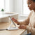 15000 mAh Power Bank: Woman using a phone on a stand while charging with a cable, showcasing convenient device usage.
