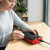 Woman using 40000mAh High Capacity Triple Input 4 USB Power Bank at a table with a charging device.