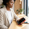 Woman using Ultra Thin Mini Portable Charger Power Bank 60000mAh at a wooden table with smartphone.