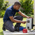 Man operating 12V 200W 0.3HP Solar Water Pump control panel outdoors.