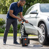 Man using a Wireless Electric Water Gun for Snow Removal & Cleaning to wash a car's wheel.