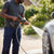 Man using Wireless Lithium Pressure Washing Machine to clean a car outdoors with a spray of water.