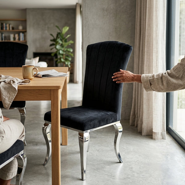 Black Velvet Upholstered Dining Chair with Silver Legs at a modern dining table in a stylish interior.