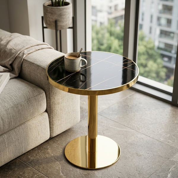 Round Black Marble Effect Dining Table with Gold Pedestal Base next to a cozy sofa with a coffee mug on top.