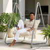 Macrame Hanging Hammock Chair with Steel Stand featuring a woman relaxing with a cup in a stylish outdoor setting.