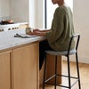 Houndstooth Bar Stool with Black Metal Frame and Footrest in a modern kitchen setting with a woman sitting