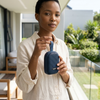 Person holding a V82 Portable Wireless Speaker outdoors on a balcony, showcasing its portable design.