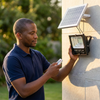 Person using a remote to control a 60W Solar Flood Light with a solar panel attached.