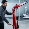 Man using a 2-Ton Hydraulic Engine Hoist for workshop lifting applications with adjustable boom and mobile caster wheels.