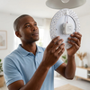 Man installing a 96W Magnetic Ceiling Light LED Chip 34cm in a modern living room.