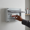 12-Way Electrical Distribution Box with a hand operating the switches on a wall-mounted unit.