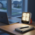 Portable Quad-Panel LED Solar Work Light illuminating a workspace next to a laptop and notebook.