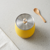 Mini Rice Cooker in vibrant yellow color with a silver lid and wooden spoon on a countertop.