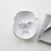 LED Face Mask – Facial LED Light Mask placed on a table next to a folded towel.