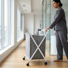 Collapsible Laundry Basket with Wheels in a modern home setting, held by a person in casual attire.