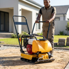 A worker using a Petrol-Powered Flat Plate Compactor on sandy ground for effective ground compaction.