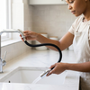 Flexible Braided Hose Assembly in use with a woman operating a kitchen faucet.
