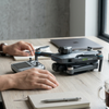 Remote Controlled Quadcopter Drone on a table with a handheld controller and notebooks nearby.