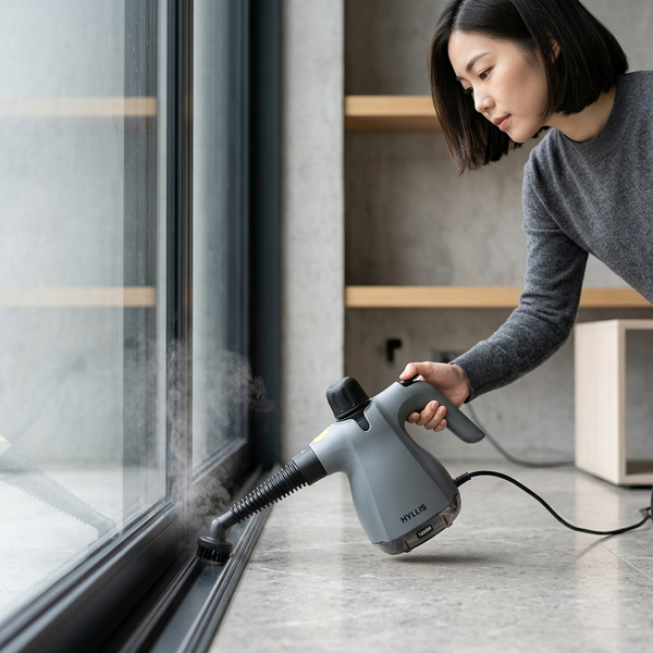 Woman using a 1200W Handheld Steam Cleaner to clean a window at home.