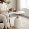 Modern Round Marble-Style Side Table with a stylish gold pedestal, occupied by a woman holding a cup.
