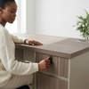 A woman using the storage drawer on a 1.2m Office Desk with Storage Drawers in a modern workspace.