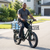 Man riding Electric Utility Bike with Front & Rear Carriers transporting water bottles on front and rear carriers.