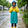 Childrens Hooded Raincoat worn by a child, providing coverage during rainy weather with a vibrant yellow and teal design.