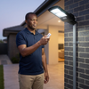 Man using remote to control 400W Solar Street Light with Motion Sensor and Remote in outdoor setting.