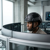 Person wearing Combat Protection Headgear in an office setting with computer monitors.