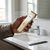 Hair Clipper in hand, rechargeable cordless hair trimmer for grooming with a comb beside the sink.