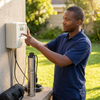 Man operating the controller for DC Submersible Pump 3IHS1.2-65-24-250 in a garden setting.