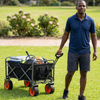 Man using Electric Camping Wagon Cart to transport sports equipment and supplies in a park.