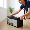 Person setting down a 12.8V 150Ah LiFePO4 Lithium Battery on a wooden floor.