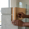 Hands installing a 12V 10 Metres LED Strip Light Reel on a wooden and concrete surface.