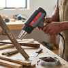 Heat Gun in use for heating wood, with metal nozzle and temperature settings visible, ideal for workshop applications.