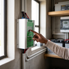 User interacting with a 24V 600W Wind Turbine and Solar MPPT Controller mounted on a wall.