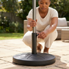 Round Outdoor Umbrella Base with Adjustable Pole Holder being installed by a user on a patio.