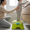 Toddler using a green Musical Toddler Potty Training Chair with adult assisting in a bathroom setting.