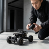 A person operating a 4WD Remote Control Off-Road Rock Crawler Truck with a remote control in a modern indoor setting.