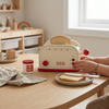 Child using the Wooden Pop-Up Toaster Playset with Breakfast Accessories on a wooden table with toast and honey.