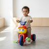 A young child riding the Kids First Pedal Tricycle Ride-On Toy, smiling while enjoying a fun indoor experience.