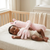Baby peacefully sleeping with Bunny-Shaped Baby Soothing Patting Pillow in a cozy crib.