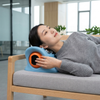A woman using the EMS Neck and Shoulder Massage Pillow while lying on a couch, enjoying a relaxing massage.