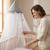 Hanging Nursery Mosquito Net Canopy with Pom-Poms placed over a crib, providing insect protection and charm.