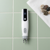 Handheld Electronic Massage Pen with Digital Display on a green tiled surface, showcasing its digital display and design.