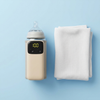 Portable USB Rechargeable Baby Bottle Warmer Sleeve next to a soft towel on a blue background with LED display at 100 degrees.