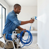 Man using High-Pressure Electric Airless Paint Sprayer Kit on a wall for smooth paint application.